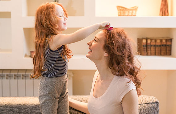 Mädchen kämmt Mutter die Haare