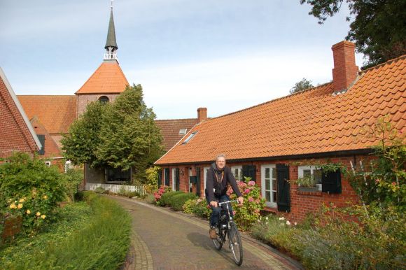 Radwege Niedersachsen – Unterwegs auf dem Nordseeküsten-Radweg durchquert ein Fahrradfahrer Rysum Radwege Niedersachsen – Unterwegs auf dem Nordseeküsten-Radweg durchquert ein Fahrradfahrer Rysum