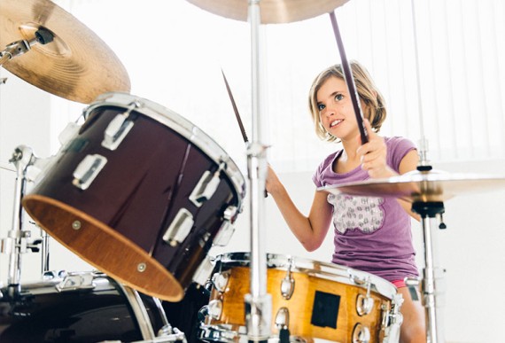 Muziekinstrumenten kinderen – Meisje oefent drummen Muziekinstrumenten kinderen – Meisje oefent drummen