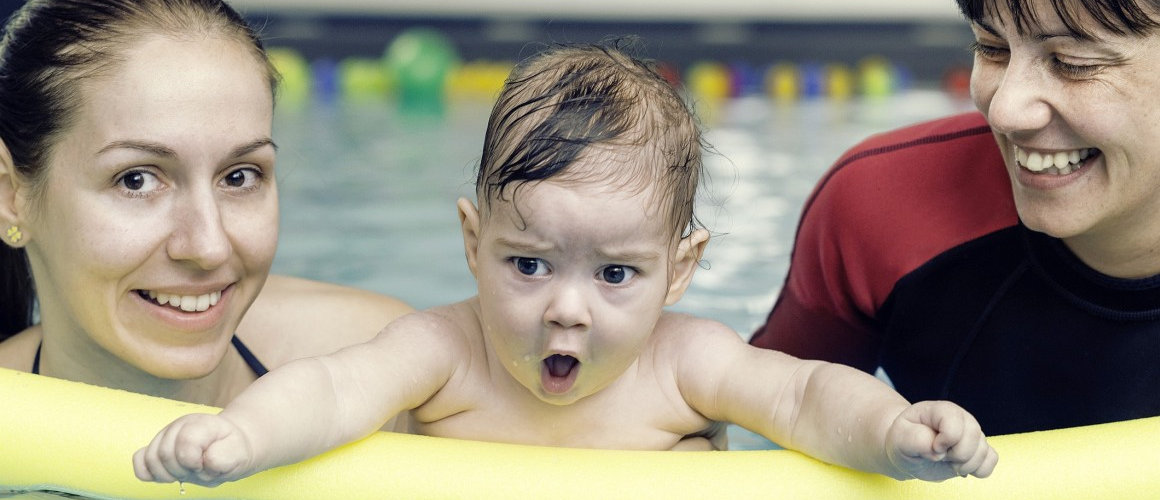 Une maman et un bébé, une frite de piscine et un maitre-nageur dans une piscine