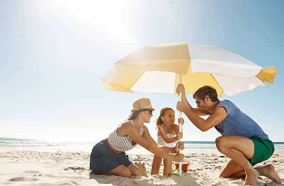 Parasol : Une famille plante un parasol sur la plage Parasol : Une famille plante un parasol sur la plage
