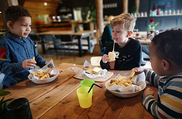Blokhut & Speelbos Sparjebird – drie kinderen eten in het restaurant Blokhut & Speelbos Sparjebird – drie kinderen eten in het restaurant