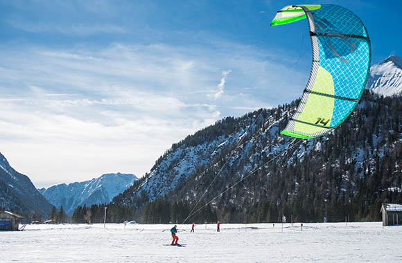 Beim Snowkiten gleitet man von einem großen Drachen gezogen über verschneite Seen und Felder Beim Snowkiten gleitet man von einem großen Drachen gezogen über verschneite Seen und Felder