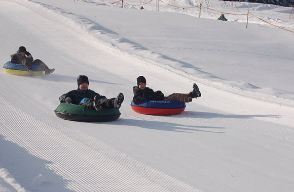 Kinder fahren auf einem Snowtube eine Schneepiste hinab Kinder fahren auf einem Snowtube eine Schneepiste hinab