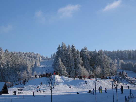 Verbandsgemeindeverwaltung Thalfang am Erbeskopf Schneebedeckter Skihang mit Wintersportlern und Familien