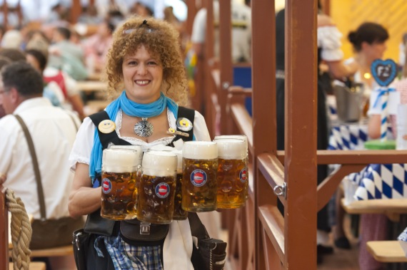 Servicekraft im Dirndl mit Masskrügen Servicekraft im Dirndl mit Masskrügen